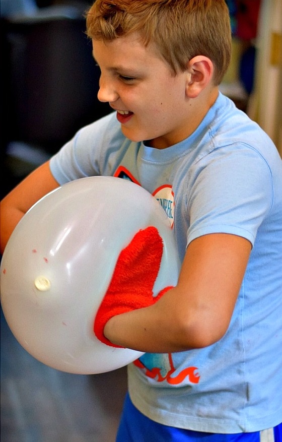 Participants playing the 'North Pole Pop' Minute to Win It game, where they aim to pop balloons using candy canes, creating a fun and festive holiday activity.