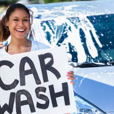 girl holding up a car wash sign to signify a car wash fundraiser event
