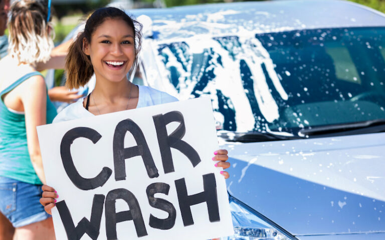 girl holding up a car wash sign to signify a car wash fundraiser event