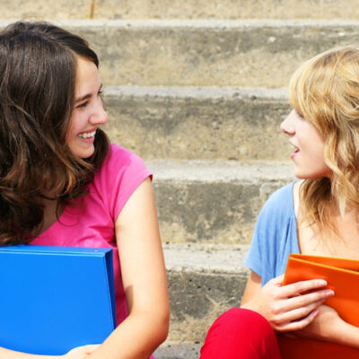 two school-aged girls talking on steps to signify getting to know someone